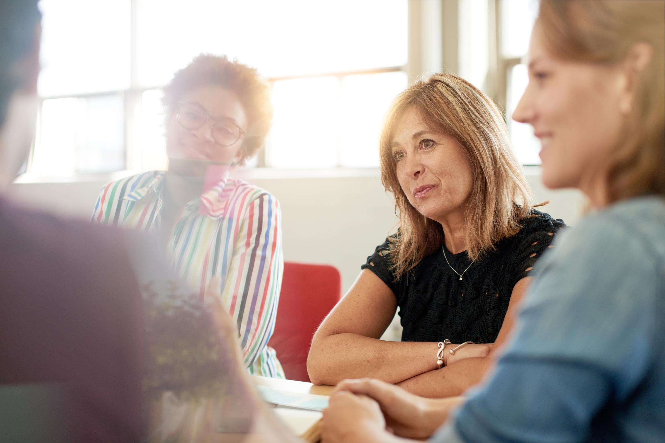 A group of women who are also social workers sat around a table discussing the benefits of the services like the social work employment service.