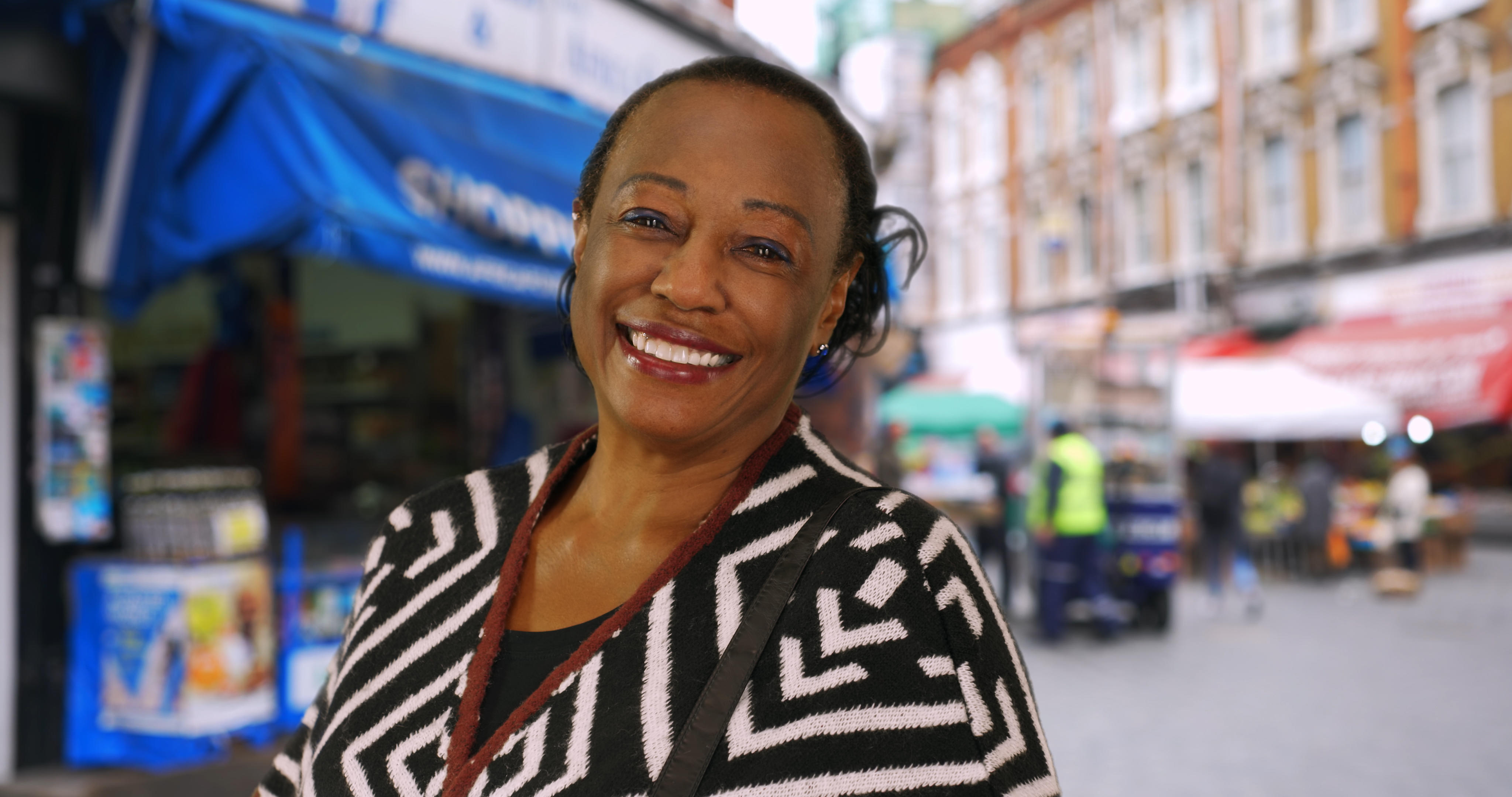 Black woman wearing a black and white striped top, smiling at the camera.